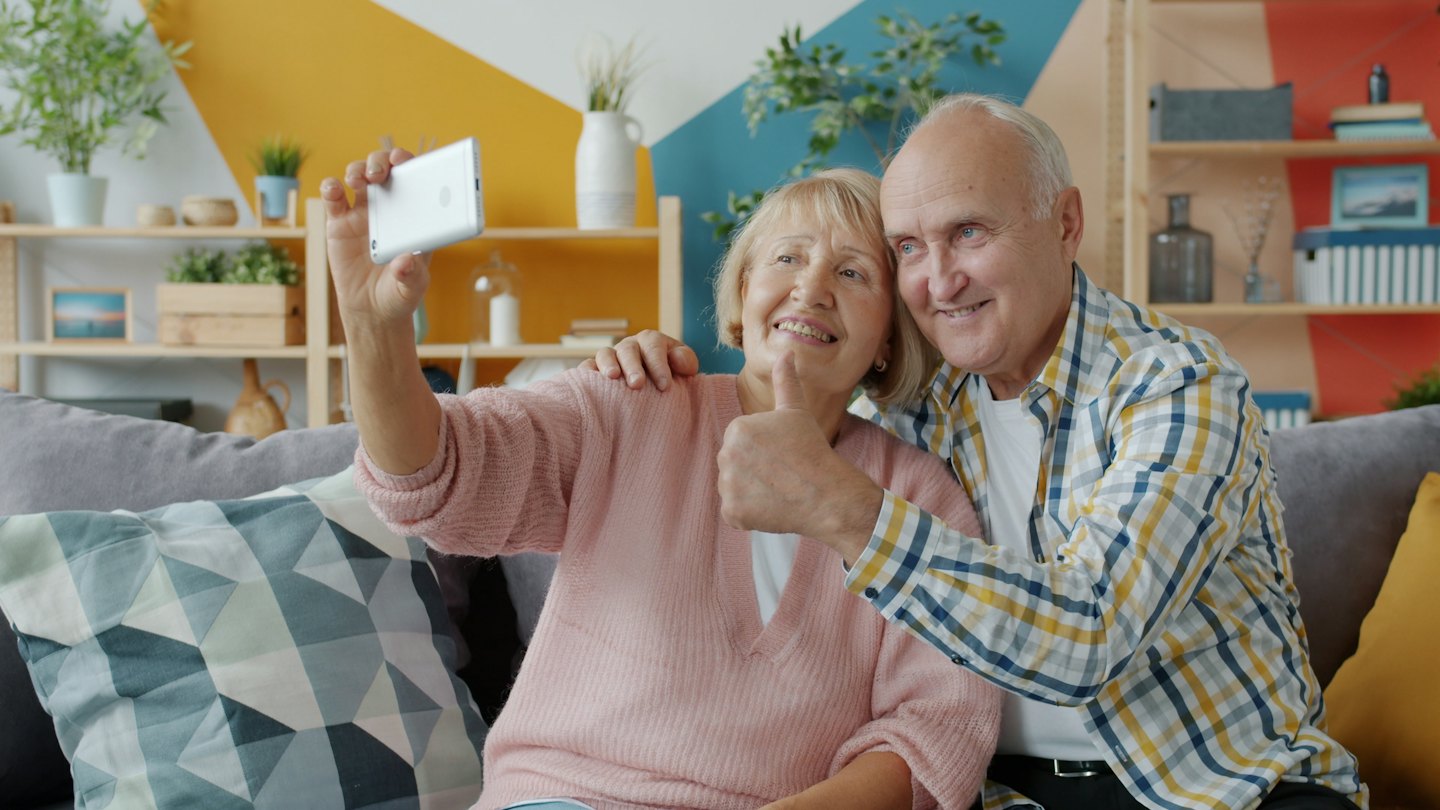 Ouder echtpaar maakt vrolijk een selfie op de bank.